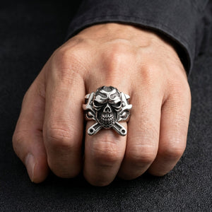 Anillo de plata de ley con calavera y llaves inglesas cruzadas usado en la mano