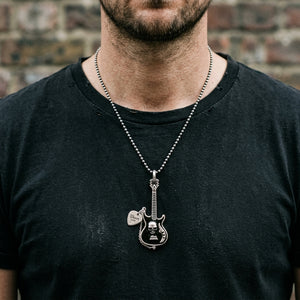 Skull electric guitar silver pendant and separately chained pick worn over a black shirt