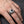 Anillo de calavera de plata esterlina con ojo marrón usado en la mano del modelo original sobre madera de carbón