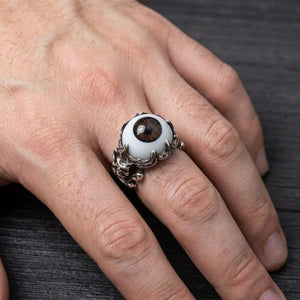Anillo de calavera de plata esterlina con ojo marrón usado en la mano del modelo original sobre madera de carbón