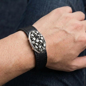 Black leather skull bracelet worn on the wrist, with the oval silver skull plate facing outward