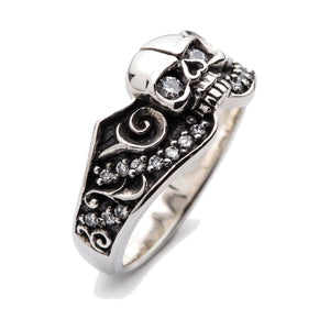 Anillo de plata de ley de calavera con ojo de diamante y volutas, vista frontal derecha del anillo sobre fondo blanco