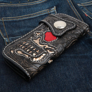 Portafoglio biker lungo in pelle con teschio, razza e cobra, vista angolata anteriore su denim