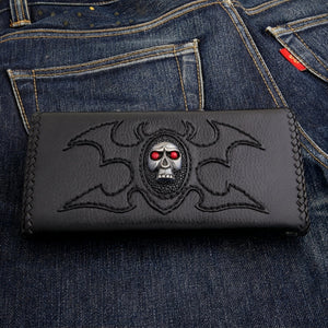 Schwarze Trucker-Geldbörse mit Totenkopf mit roten Augen auf einem ovalen Rochenlederfeld und flügelartigen Tribal-Nähten.