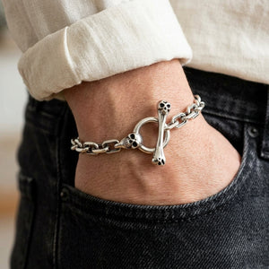 Skull and bone toggle bracelet worn on a wrist, leaving the silver closure clearly visible.