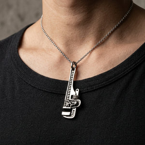 Sterling silver skull wrench pendant on a slim 2 mm silver chain worn by a male model