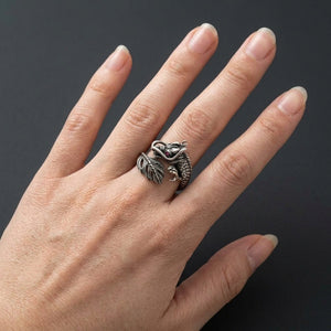 Small silver dragon wrap ring with red eye and featherlike tail worn on a hand