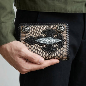 A hand holds the snake trifold at waist level, showing the black stingray cross and two flame snaps.