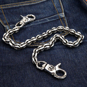 Die Flame-Blossom-Geldbörsenkette aus massivem Silber mit maßgefertigten Gliedern auf einem dunklen Denim-Hintergrund ausgelegt