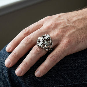Anillo gótico de plata esterlina con cruz de estrella y filigrana, llevado en un dedo medio en un primer plano natural de la mano