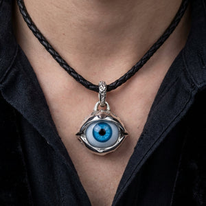 Blue eyeball pendant with silver claw setting on black braided leather cord necklace worn on model's neck, gothic biker jewel