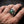 Gothic silver ring with large emerald green gemstone held by claw prongs and dragon scale detailing worn on a man's finger ag