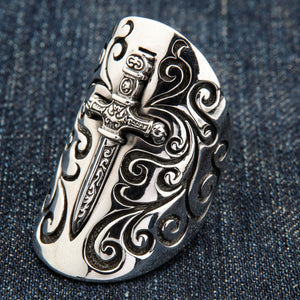 A sterling silver knight shield ring with intricate gothic scrollwork and a polished dagger.