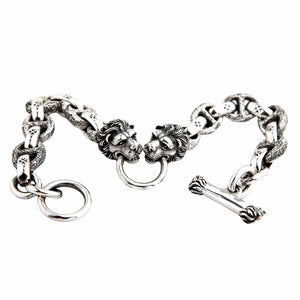 Sterling silver lion head bracelet with cross link chain displayed flat showing dual lion heads and T-bar clasp