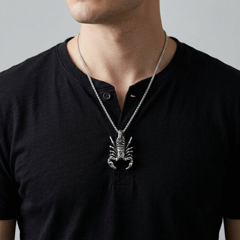 Sterling silver scorpion pendant on a silver chain worn over a black henley shirt.