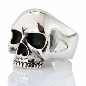 Sterling silver skull ring with a polished dome, dark eye sockets and defined upper teeth, front angled view.