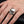 Sterling silver skull ring with a garnet eye worn on hand for scale