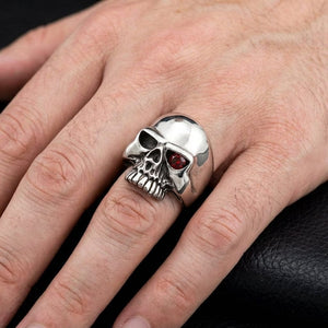 Sterling silver skull ring with a garnet eye worn on hand for scale