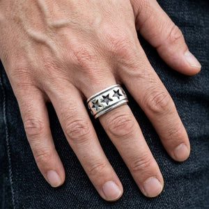 Anillo Star Band de plata de ley, llevado en un dedo corazón en un primer plano natural de la mano