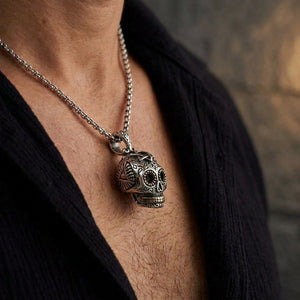 Pendentif tête de mort mexicaine porté par un homme sur fond de studio en pierre sombre