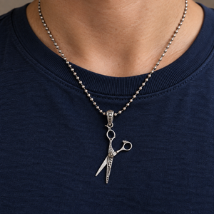 Engraved Scissors Sterling Silver Pendant with engraved open blades over a navy shirt.