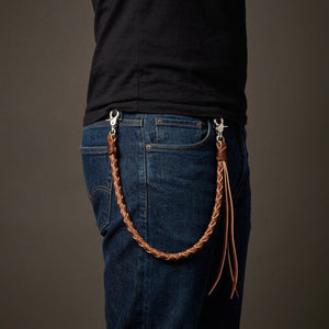Ljusbrun flätad plånbokskedja i läder med tofsar buren på blå jeans till en svart T-shirt