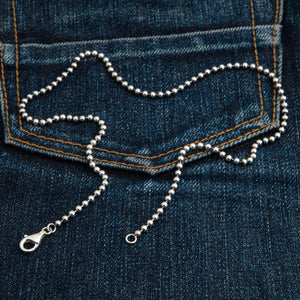 3 mm sterling zilveren bolletjesketting. De gepolijste kralenketting buigt over een gestikte spijkerbroekzak.