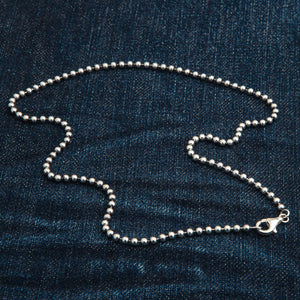 3 mm sterling zilveren bolletjesketting. Een brede lus van de zilveren kralenketting wordt getoond op denim met de karabijnsluiting aan één kant.