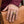 A hand with a burgundy cuff wears the rectangular tiger-eye ring while resting on a tan leather bag.