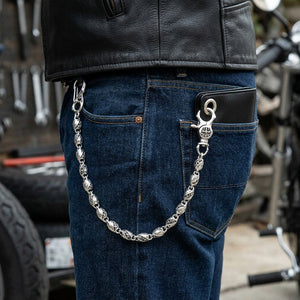 Tribal barrel-link silver wallet chain draped from a front jeans belt loop to the metal grommet of a wallet in a rear pocket.