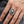 Anillo de calavera y hoja tribal en plata de ley puesto en una mano adulta, mostrando el detalle de la parte frontal y los hombros.