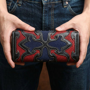 Cartera de mantarraya roja con cruz tribal sostenida en las manos