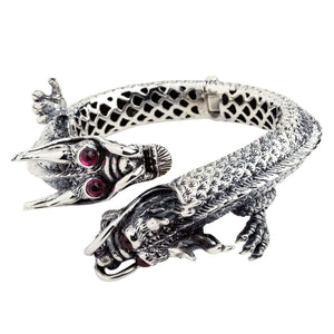 Bracciale cuff in argento a doppio drago con pietre rosse per gli occhi, teste sovrapposte e dettagli di squame in rilievo.