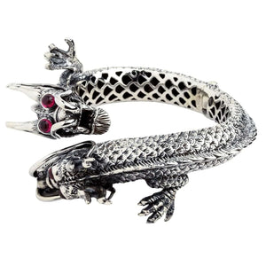 Bracciale in argento con draghi ruotato per mostrare i castoni degli occhi, le zampe artigliate e i corpi sovrapposti.