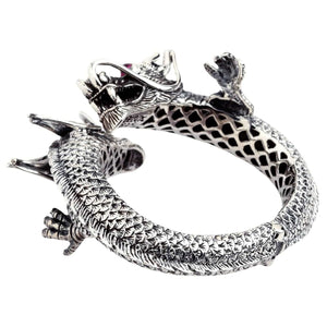 Parte inferiore angolata del bracciale in argento che mostra ritagli a grata e zampe di drago in rilievo.