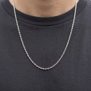 La fine chaîne marine en argent drape naturellement une chemise anthracite, révélant ses maillons à barre centrale.