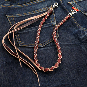Corrente para carteira em couro bovino trançado bicolor, fechos duplos de metal e franjas longas sobre jeans