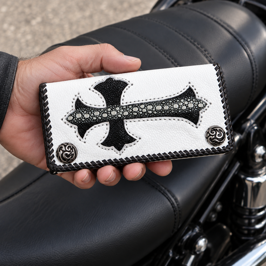 White cowhide biker wallet with black stingray cross held beside a black motorcycle seat