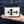 White leather biker wallet supported in one hand, showing the sideways black stingray cross and braided border