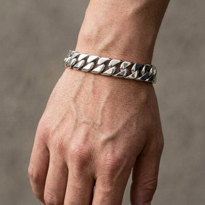 Pulseira larga de malha cubana em prata de lei polida usada sobre a parte superior do pulso de um homem