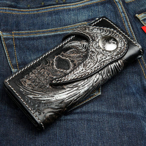Biker-lommebok i sort rokkeskinn med vinget hodeskalle, vinklet lukket hodeskallefront og concho på denim